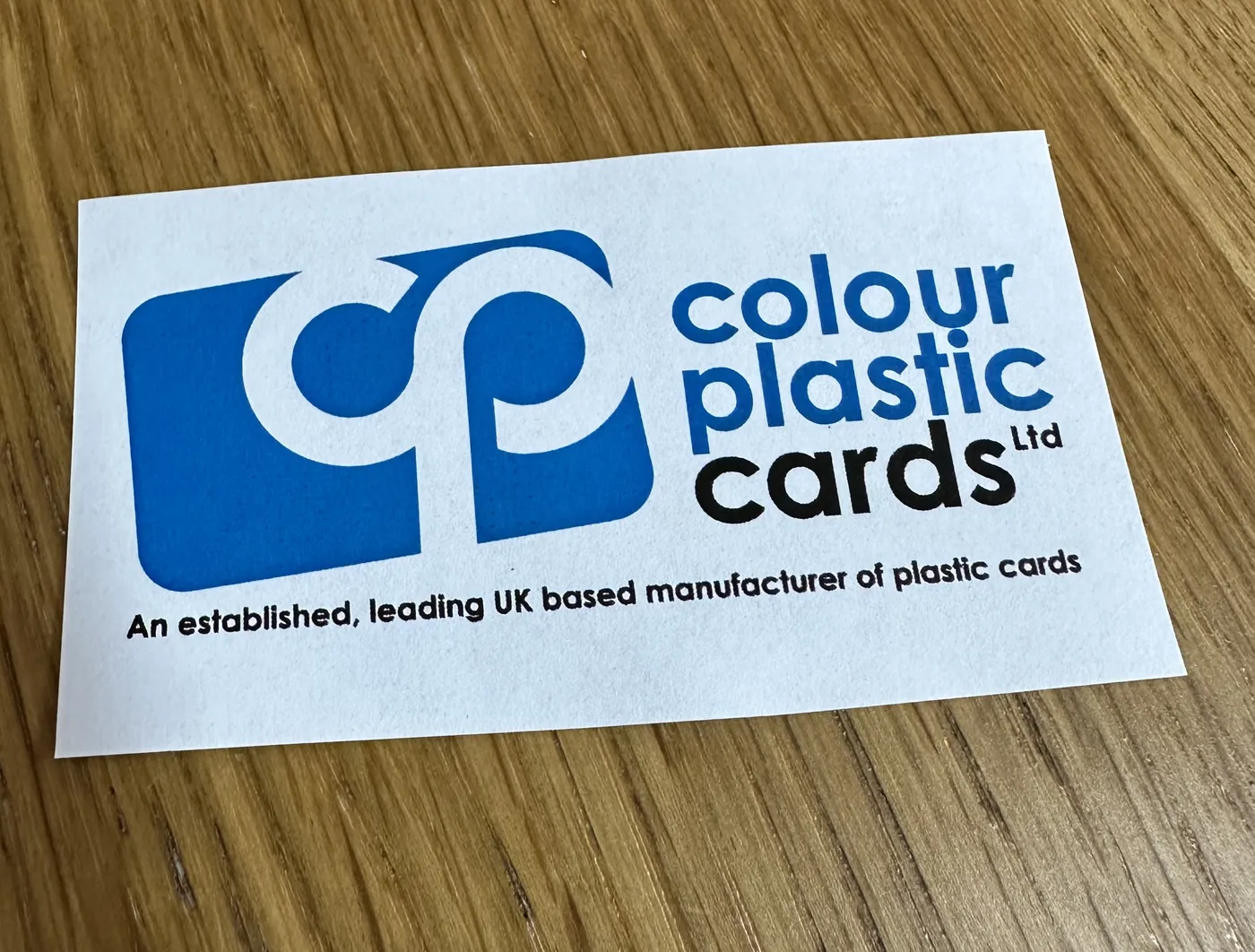 A photograph of a printed copy of the logo lying on a wooden desk, taken at an angle