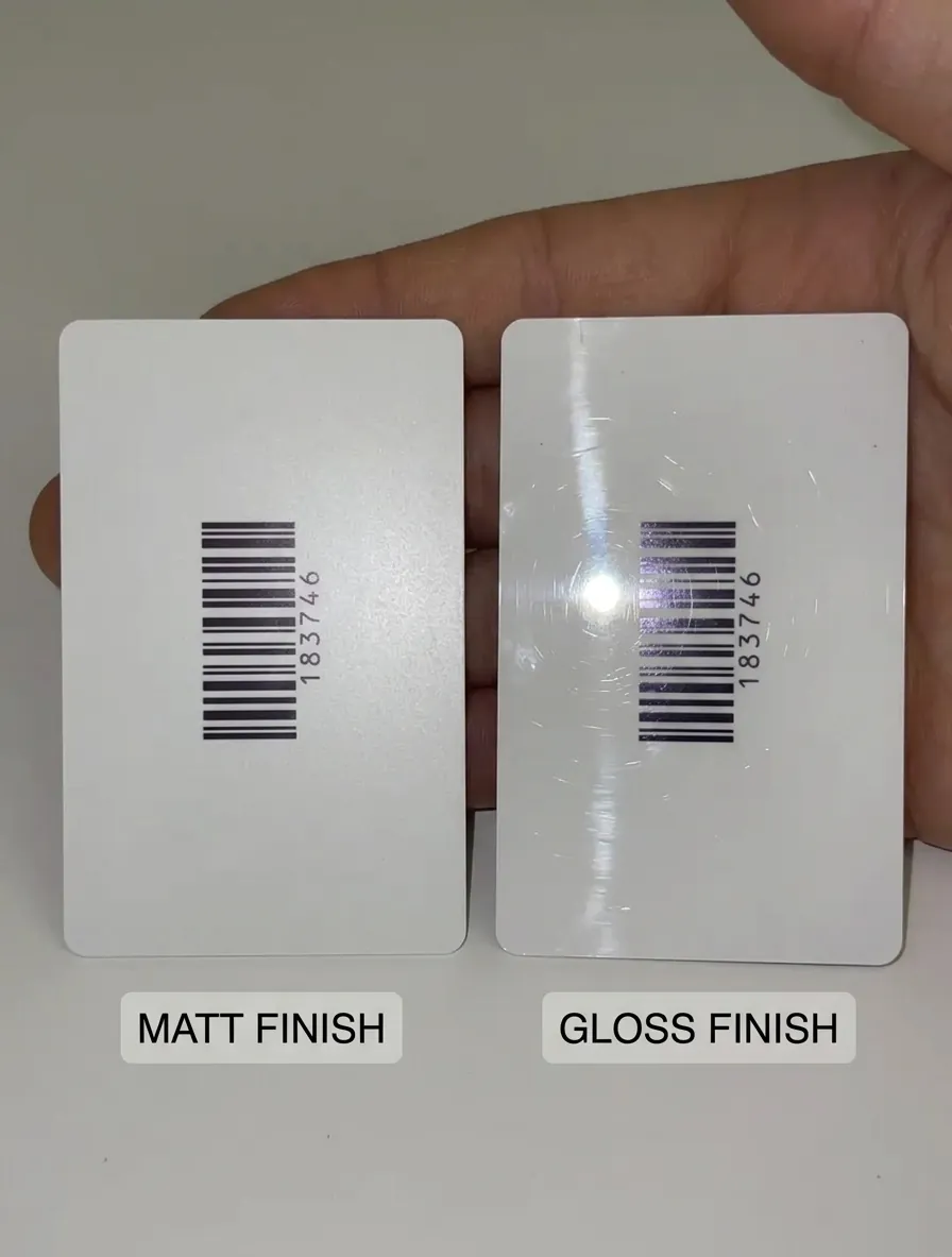 two white plastic cards with the same barcode held side by side, the Matt Finish card on the left reading cleanly and the Gloss Finish card on the right with a bright light reflection across the barcode