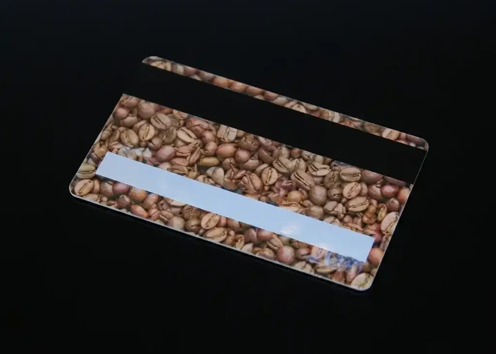 the back of a plastic card printed with coffee beans, with a black magnetic stripe and a white signature panel