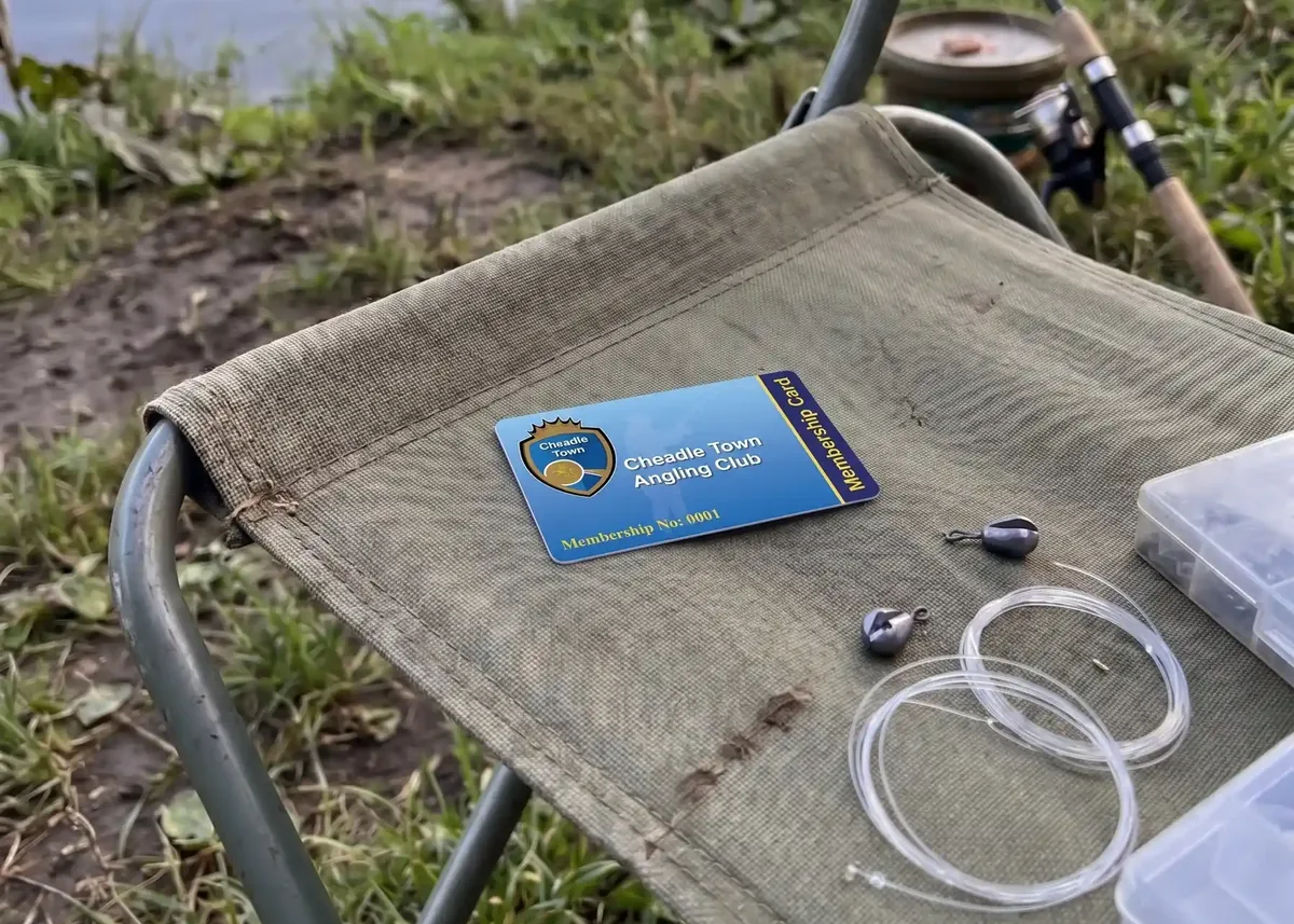 Blue angling club membership card on a bankside chair with fishing line