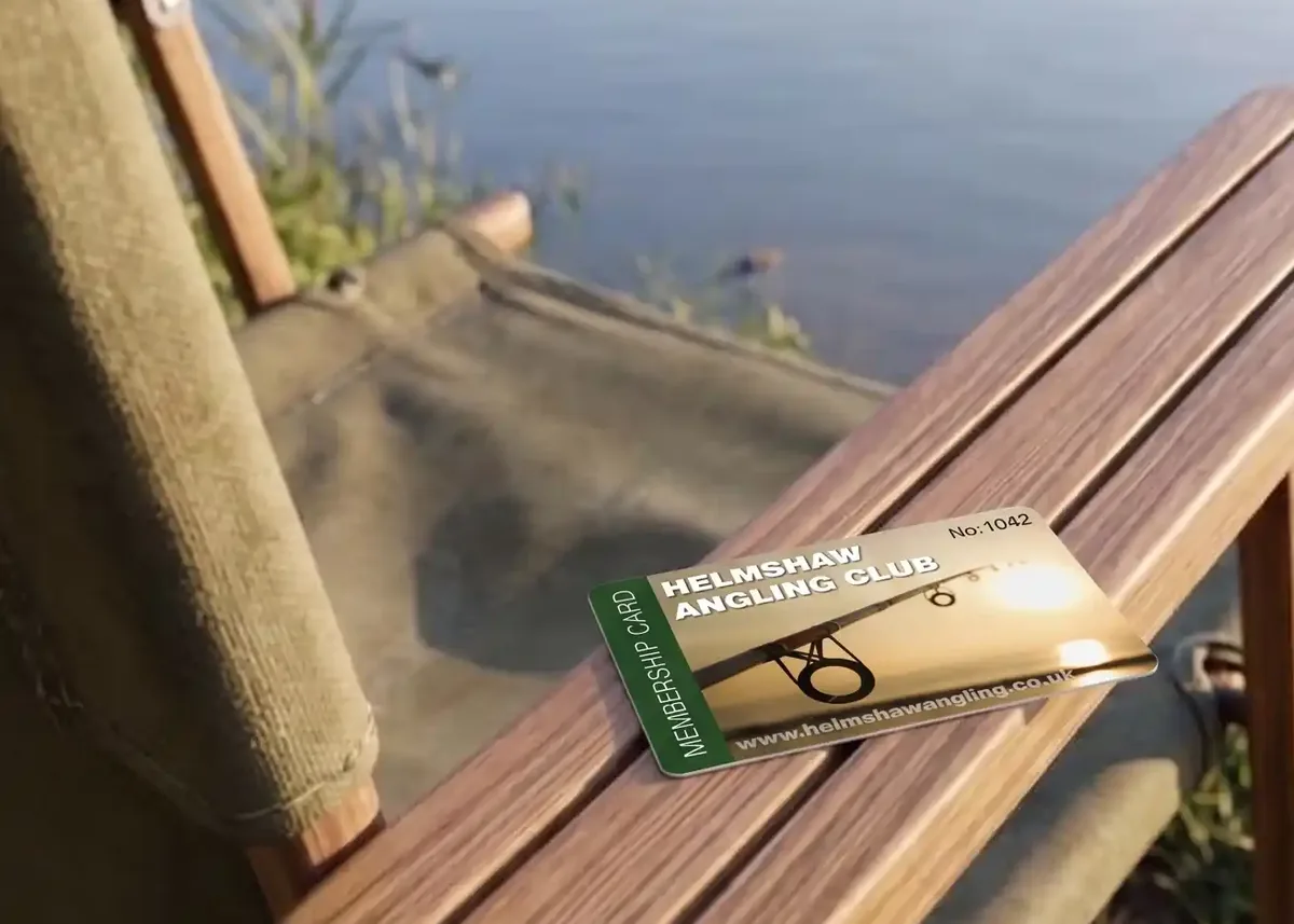 Helmshaw Angling Club numbered membership card on a lakeside chair