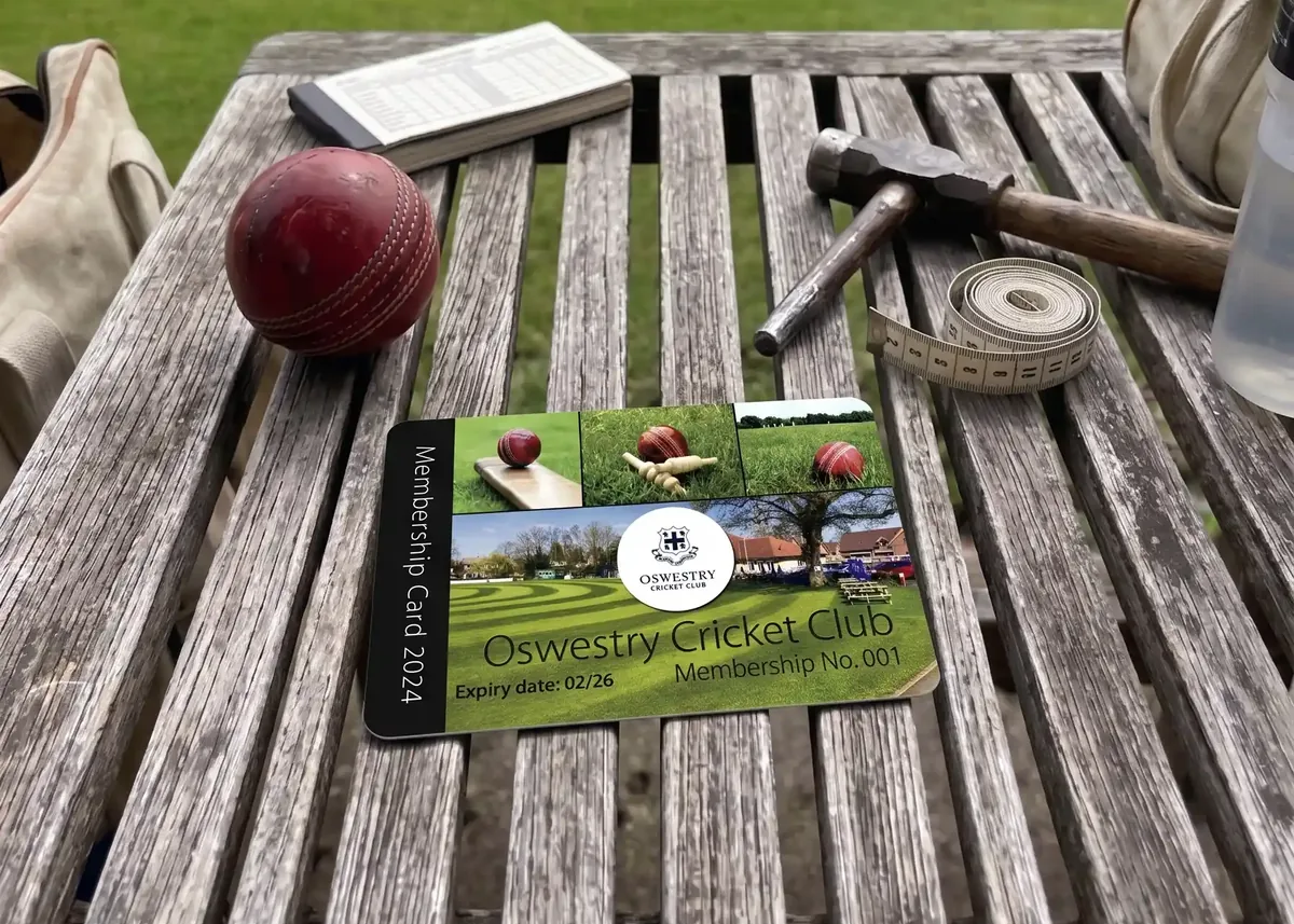 Oswestry Cricket Club membership card on a bench beside a cricket ball