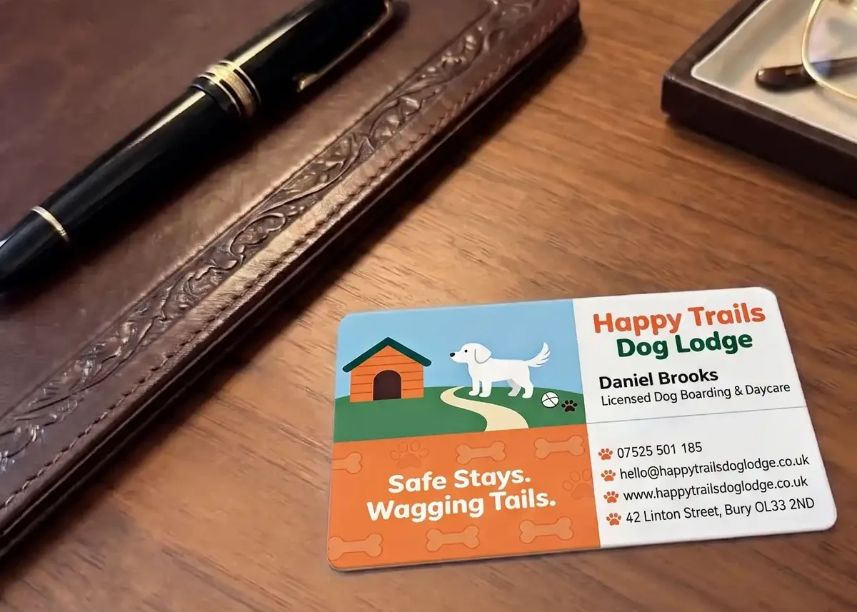 Happy Trails Dog Lodge plastic business card on a leather desk