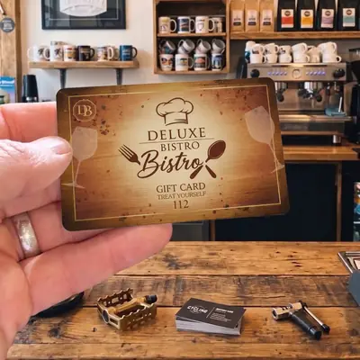 Deluxe Bistro gift card held up in a cafe