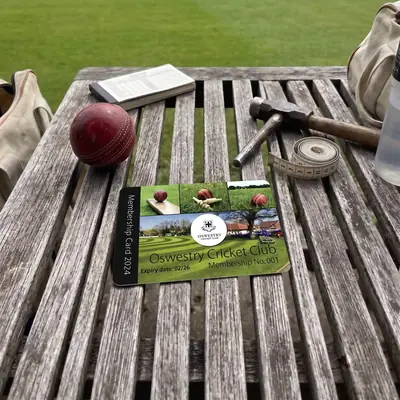 Oswestry Cricket Club membership card on a bench beside a cricket ball